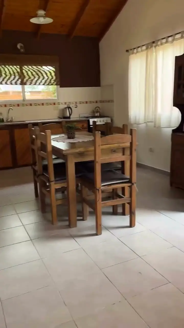 La cocina-comedor con techo de madera, mesada, mesa con sillas de madera y una ventana al parque.