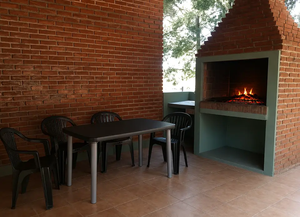 La parrilla de ladrillo de la galería con el fuego encendido y la mesa lista al lado.